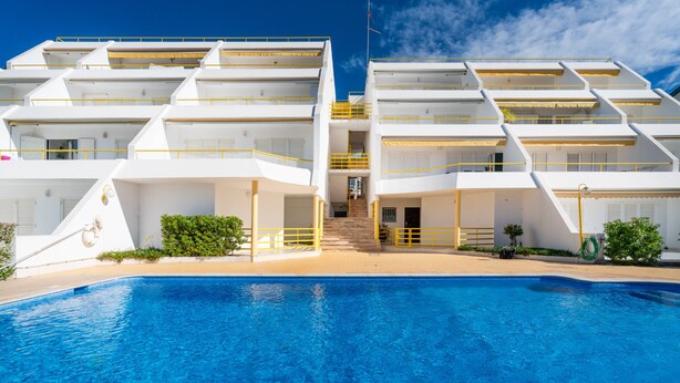 A modern hotel with a pool, multiple balconies, and a clear sky. - Albufeira Beach Apartment (Guia)