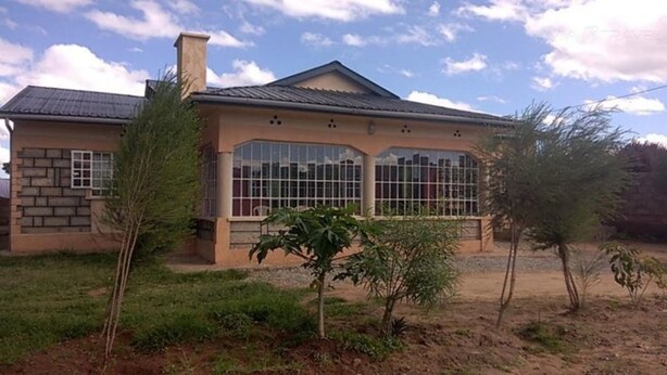Una casa de una sola planta con techo de tejas, ventanas amplias y fachada de piedra.