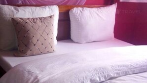 Una cama con edredón blanco, almohada acolchada color beige y almohada blanca.
