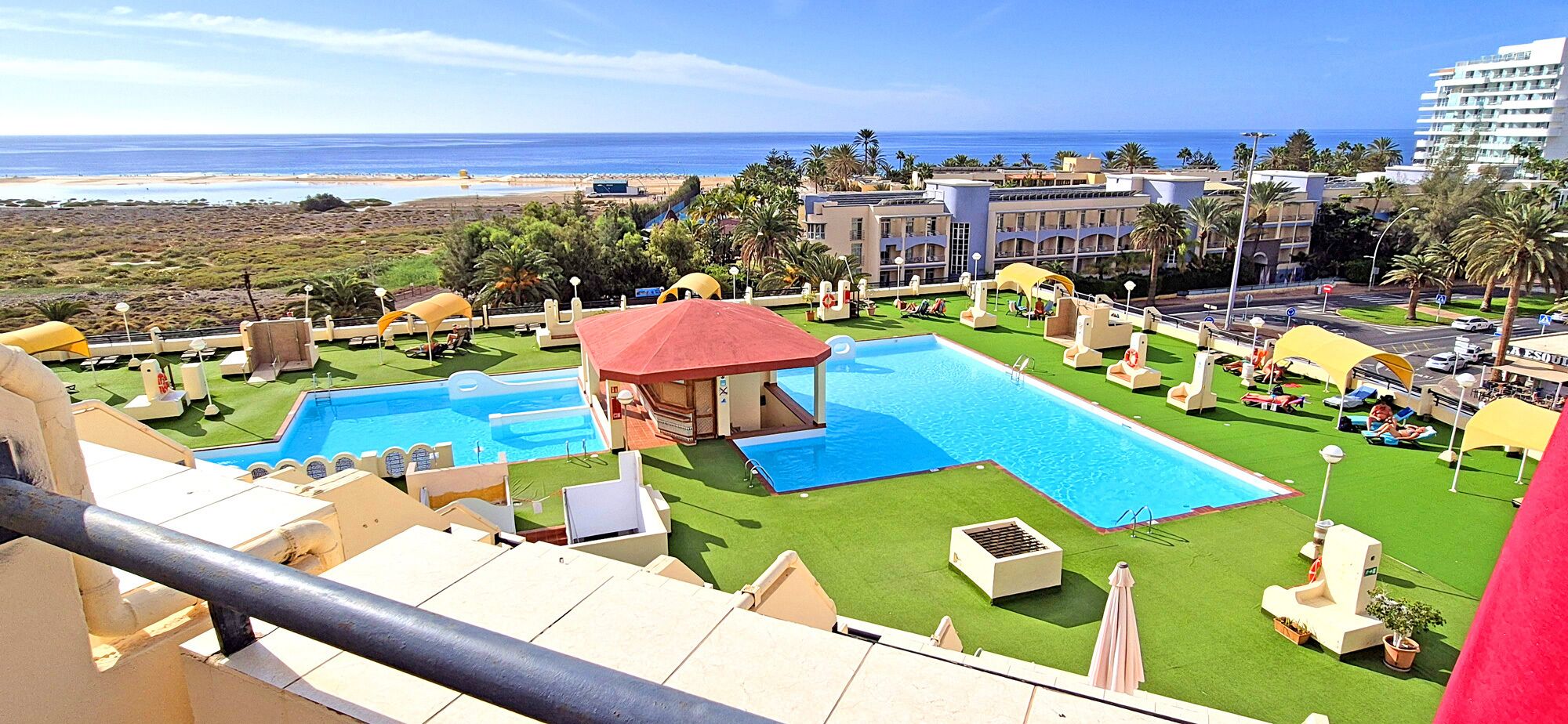 A resort with multiple swimming pools, a beach view, and palm trees.