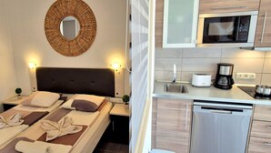 A hotel room with a bed, bedside lamps, a round mirror, a small plant, and a kitchen with a microwave, toaster, coffee maker, and dishwasher. - Apartment BUENA VISTA (Palm Garden) Morro Jable, sea view, pool (Morro Jable)
