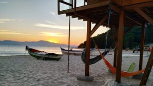 A beach with a wooden structure, hammocks, and boats.