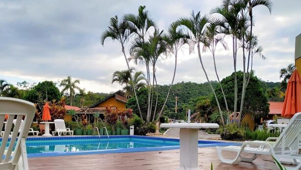 A pool area with lounge chairs, a table, and palm trees.