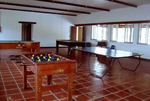 Enjoy games and leisure activities in this spacious indoor area featuring a foosball table, pool table, and ping pong table.
