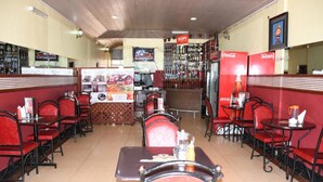 A restaurant with booths and tables, a bar area, and a Coca-Cola refrigerator. - Monalisa Hotel Thika (Thika)