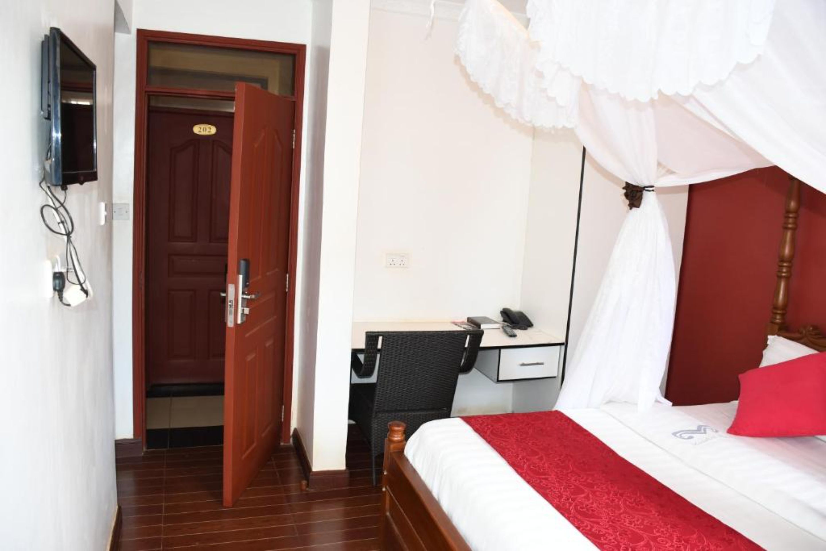 Une chambre d’hôtel avec un lit, un bureau, une chaise, une télévision et une porte.