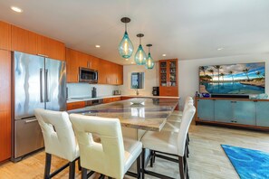 A modern kitchen with a large island, stainless steel appliances, and pendant lighting.