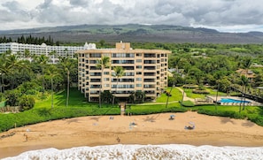 A hotel with a central courtyard, surrounded by lush greenery and a beach with sun loungers. - Luxurious, Modern Oceanfront Escape –Polo Beach Club 602 with Breathtaking Views (Makena, Maui)
