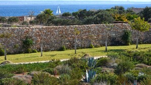 Un mur de pierre offrant une vue sur la mer, avec un voilier visible au loin.