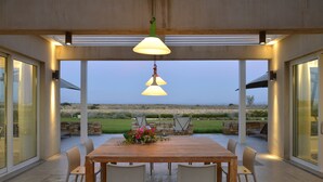 Un espace de restauration en plein air avec une table et des chaises en bois, un arrangement floral en guise de décoration centrale et une vue sur le paysage.