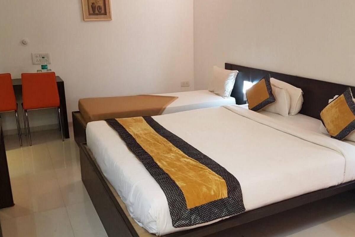 Una habitación de hotel con una cama grande, una mesita de noche, una silla y un escritorio con su silla.