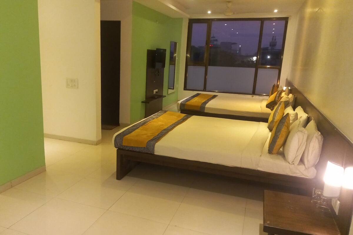 Habitación de hotel con una cama grande, una mesita de noche, un espejo y una ventana con vistas a la ciudad.