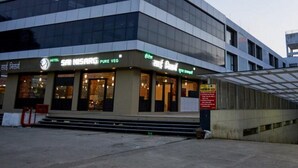 A hotel with a modern facade, signage for 'SAINSARG' and 'HOTEL SANISARG PURE VEG', and a staircase leading to the entrance. - Hotel Sai Nisarg (Rahata)