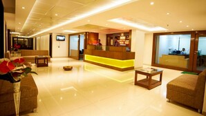 A hotel lobby with a reception desk, sofas, a coffee table, and a TV screen. - Hotel Sai Nisarg (Rahata)