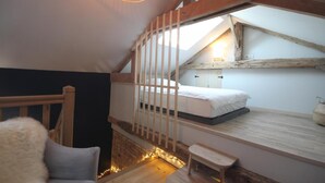 A loft bedroom with a wooden bunk bed, a small bench, and a sloped ceiling with exposed beams. - The Château Orangerie (Hugleville-En-Caux)