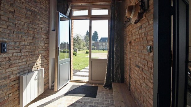 A narrow hallway with a wooden ceiling and brick walls, leading to a glass door opening to a garden. - The Château Orangerie (Hugleville-En-Caux)