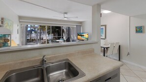 Eine moderne Küche mit Spüle aus Edelstahl, einem Fenster mit Blick auf einen Strand und einem Deckenventilator.