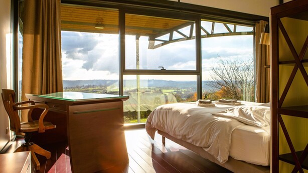 Ein Schlafzimmer mit großem Fenster, Schreibtisch und Bett.
