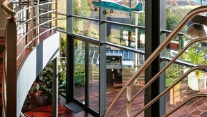 Ein großzügiger Innenraum mit hoher Decke, großen Fenstern mit Blick auf die Landschaft und einer Treppe mit Glastrennwand.