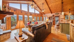 A spacious cabin with a large living area, wooden ceiling, and large windows offering views of the outdoors. - Amazing 5 br cabin-amazing mtn views & mins to NP (Sevierville)