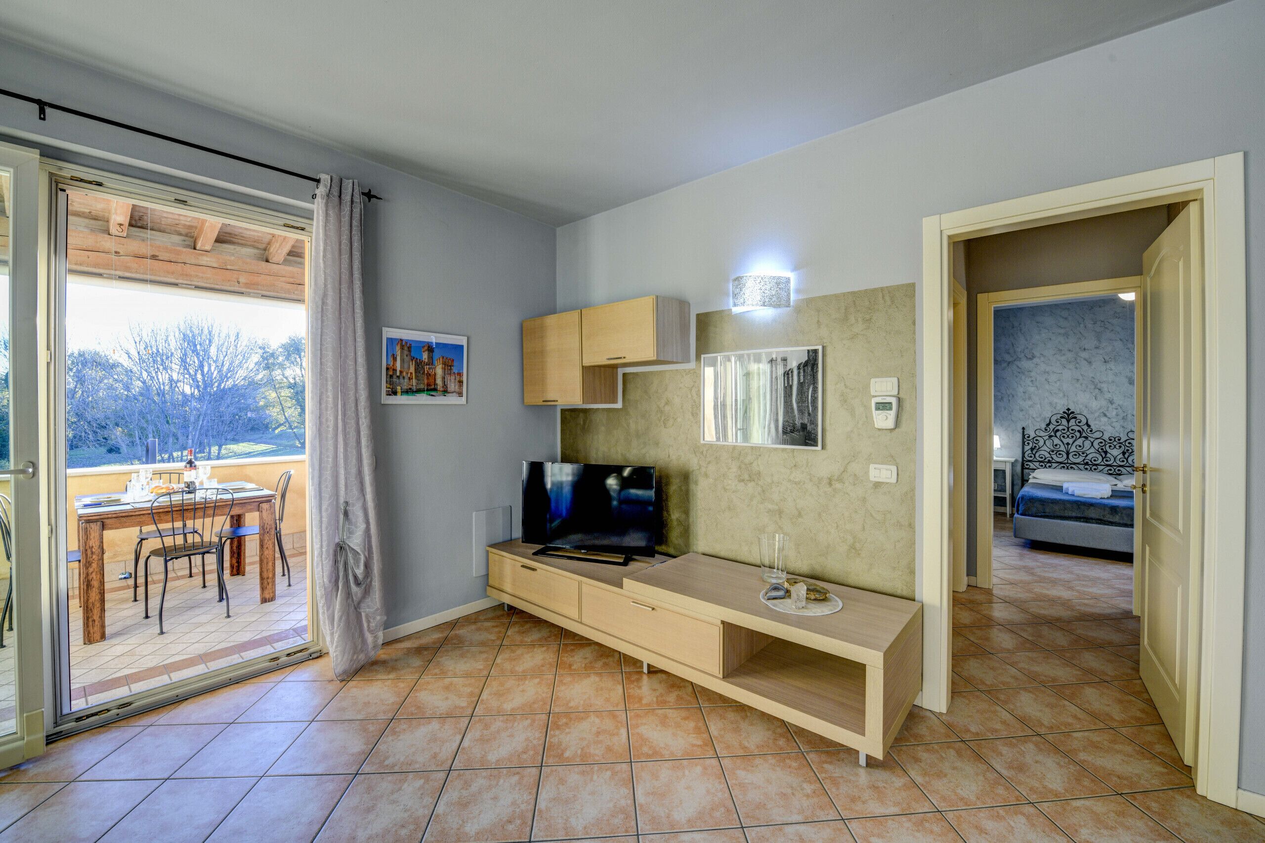 Una sala de estar moderna con televisor, armarios de madera y un comedor con mesa y sillas.