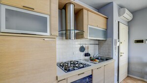 Une cuisine moderne dotée d’appareils électroménagers en acier inoxydable, de meubles en bois et d’un revêtement mural en carreaux.
