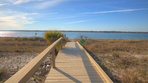 Un muelle de madera que conduce a una playa con vista despejada del océano.