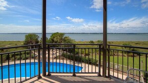Un balcón con vista a una piscina y una extensión de agua.