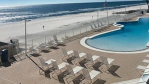 Un espace piscine avec des chaises longues et une vue sur la plage et l’océan.