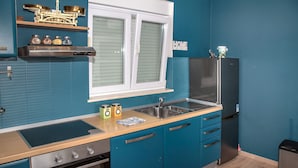 Una cocina moderna con armarios color turquesa, un refrigerador de acero inoxidable, un horno empotrado y una ventana con persianas.