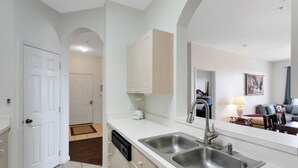 A modern kitchen with white cabinetry, stainless steel sinks, and a dishwasher. - Windsor Palms 3 Bed Condo In Gated Resort 3 Bedroom Condo by RedAwning (Kissimmee)