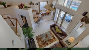 A spacious living area with a high ceiling, a dining area, and a staircase. - Resort 5 Bed Private Pool & Spa, Game Room Home 5 Bedroom Villa by RedAwning (Kissimmee)