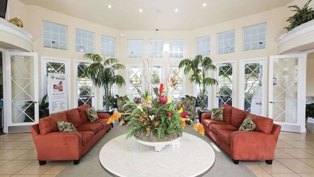 A spacious lobby with two sofas facing a central round table surrounded by tropical plants. - Resort 5 Bed Private Pool & Spa, Game Room Home 5 Bedroom Villa by RedAwning (Kissimmee)