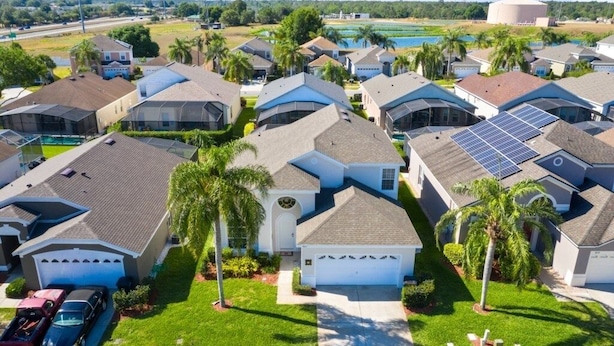 Un quartier résidentiel où les maisons sont dotées de panneaux solaires, d’une piscine et d’une pelouse bien entretenue.