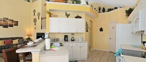 A compact kitchen with white cabinets, a dining area with a table and chairs, and a small island with a sink.