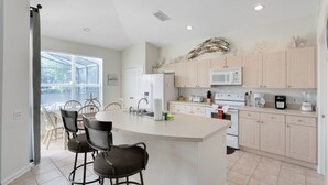 A modern kitchen with a central island, white cabinets, and a large window providing natural light. - 4 Bedroom/3 Bath South Facing Pool/Spa Villa 4 Villa by RedAwning (Kissimmee)