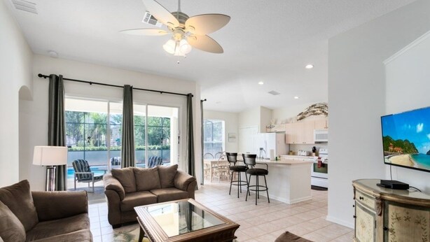 A spacious living room with a glass coffee table, two sofas, and a ceiling fan. - 4 Bedroom/3 Bath South Facing Pool/Spa Villa 4 Villa by RedAwning (Kissimmee)