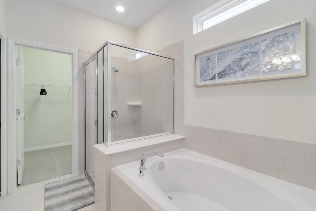 A modern bathroom with a glass-enclosed shower, a freestanding bathtub, and a framed artwork on the wall.