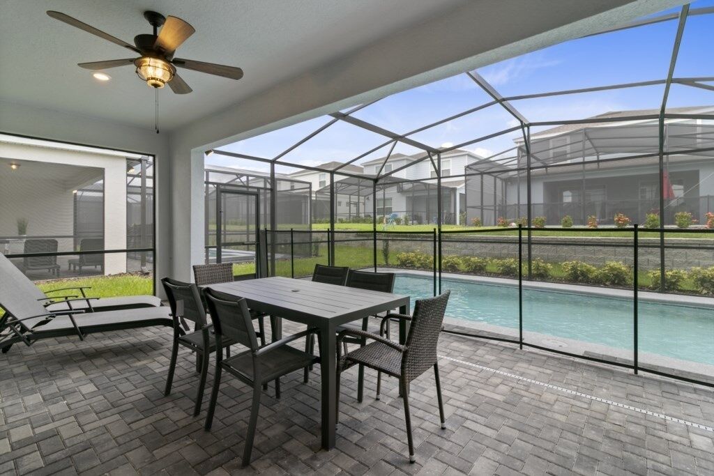 A covered patio area with a pool, outdoor seating, and a ceiling fan.