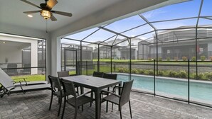 A covered patio area with a pool, outdoor seating, and a ceiling fan.