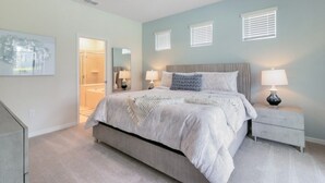 A bedroom with a bed, bedside tables, a ceiling fan, and a walk-in closet.