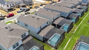 A residential area with modern houses, swimming pools, and a well-maintained lawn.