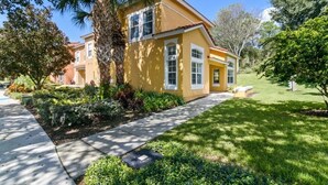 A yellow house with a number 2736, surrounded by well-maintained lawns and trees. - Disney Area 4 Bed Emerald Island 4 Bedroom Townhouse by RedAwning (Kissimmee)