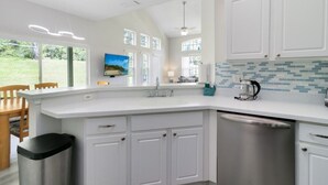 A modern kitchen with white cabinetry, a stainless steel dishwasher, and a tiled backsplash. - Disney Area 4 Bed Emerald Island 4 Bedroom Townhouse by RedAwning (Kissimmee)