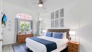 A bedroom with a bed, bedside tables, a ceiling fan, and a window with curtains. - Disney Area 4 Bed Emerald Island 4 Bedroom Townhouse by RedAwning (Kissimmee)