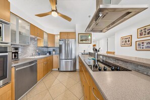 A modern kitchen with stainless steel appliances, wooden cabinets, and a tiled backsplash.