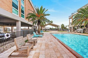 A poolside area with lounge chairs, a lifebuoy, and a clear blue pool.