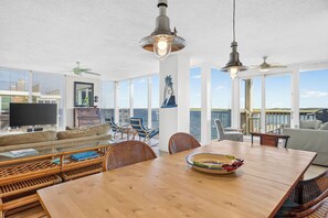Un vaste espace de vie doté d’une grande table en bois, de sièges confortables et offrant une vue sur l’océan.
