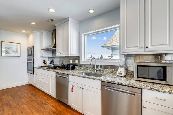 Enjoy cooking in this well-equipped kitchen with a dishwasher, oven, microwave, and large window offering a view.