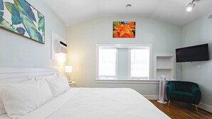 Un dormitorio con una cama grande, un calentador portátil, un televisor y una ventana con persianas.